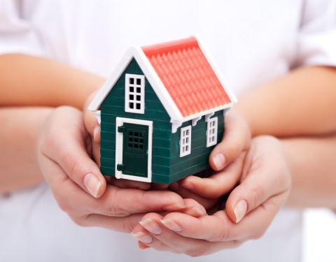 People holding toy house in hands
