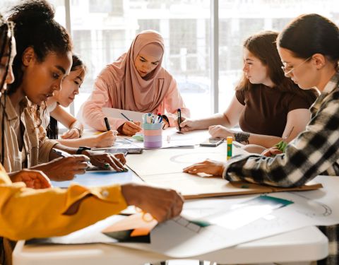 students sitting around a table making posters