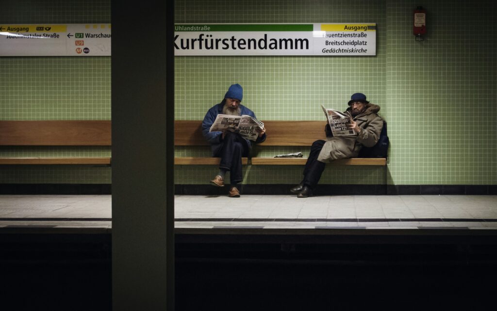 two older men sit at a train station