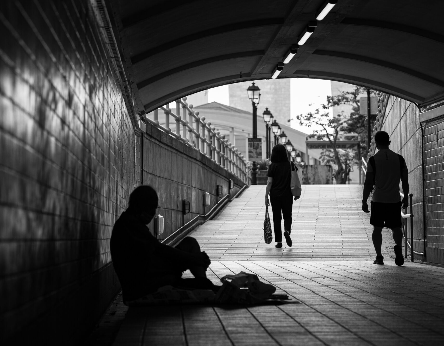 Person sitting under bridge